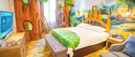 A bedroom with a bed, a chair, a bench, a TV, and a mural of a tree and landscape.