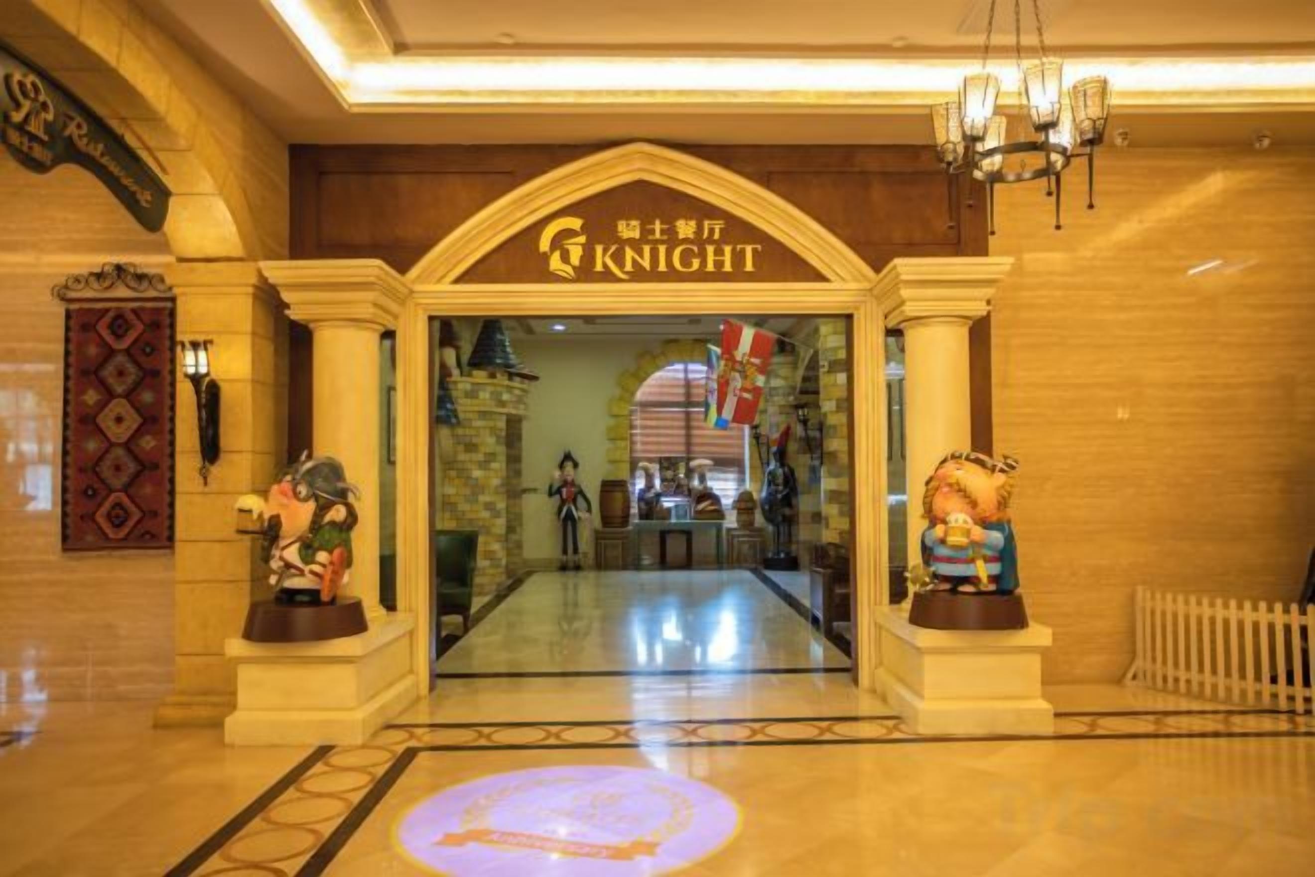 Entrada de hotel com uma placa indicando 'KNIGHT' e duas estátuas de cada lado.