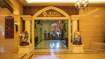 Entrada de hotel com uma placa indicando 'KNIGHT' e duas estátuas de cada lado.