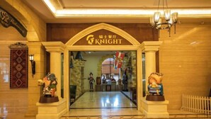 The entrance to the Knight hotel with a clear view of the lobby area, including a reception desk and decorative statues. - Knight's Hotel Europark Resort (Qihe County)