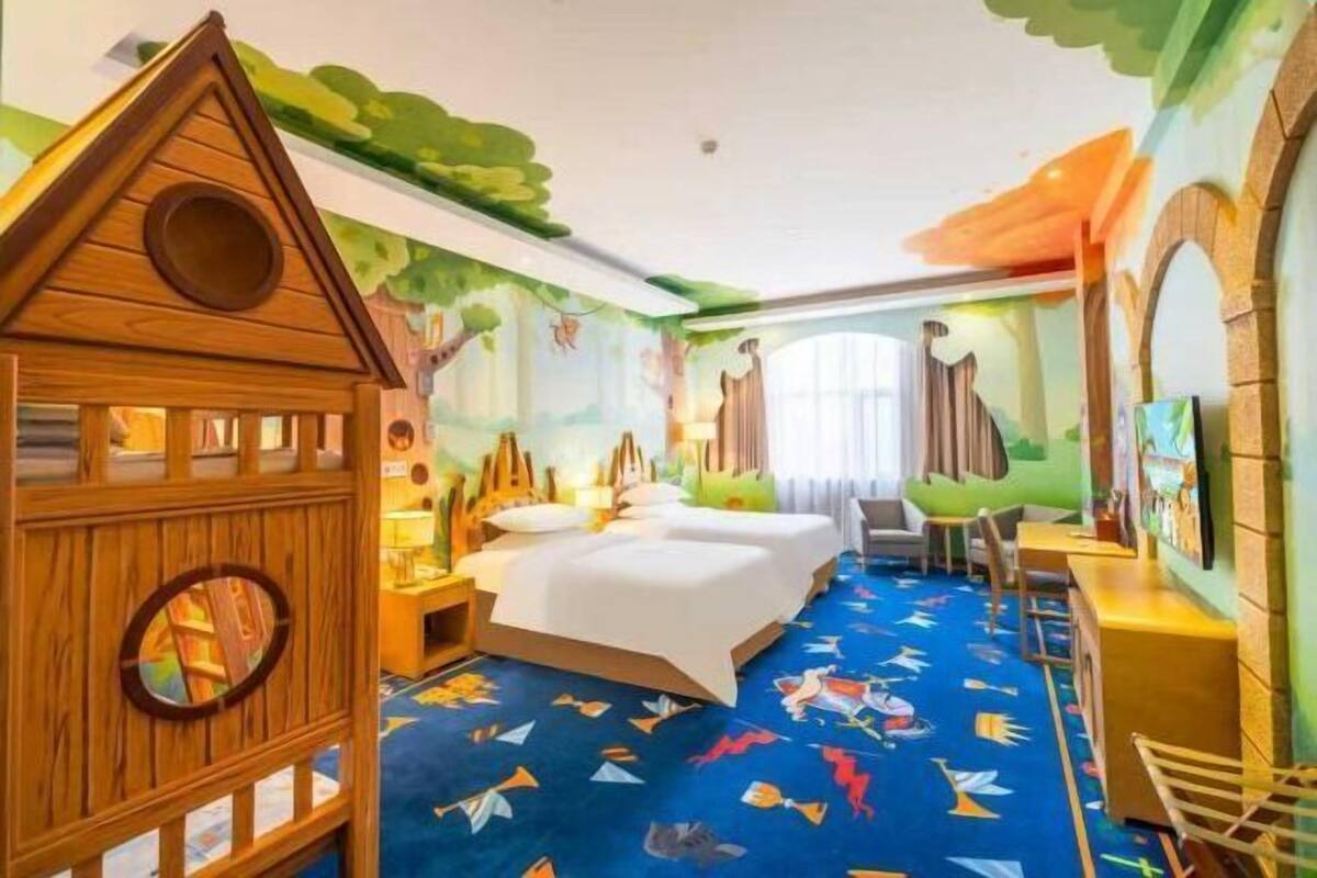 Une chambre d’enfant avec un lit, une maison de jeu et une fresque murale colorée.