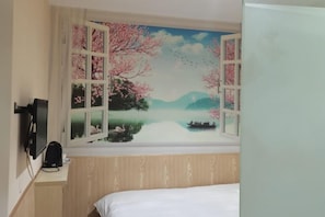 A bedroom with a large window, a bed, a TV, and a small table with a lamp.