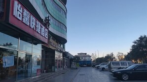 A hotel with a modern facade, large windows, and a parking lot with several cars. - Beijing Yixin Express Hotel (Miyun Great Wall Huandao Branch) (Beijing)