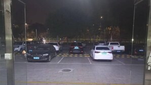 A parking lot with several cars parked, including a white sedan and a black SUV. - Beijing Yixin Express Hotel (Miyun Great Wall Huandao Branch) (Beijing)