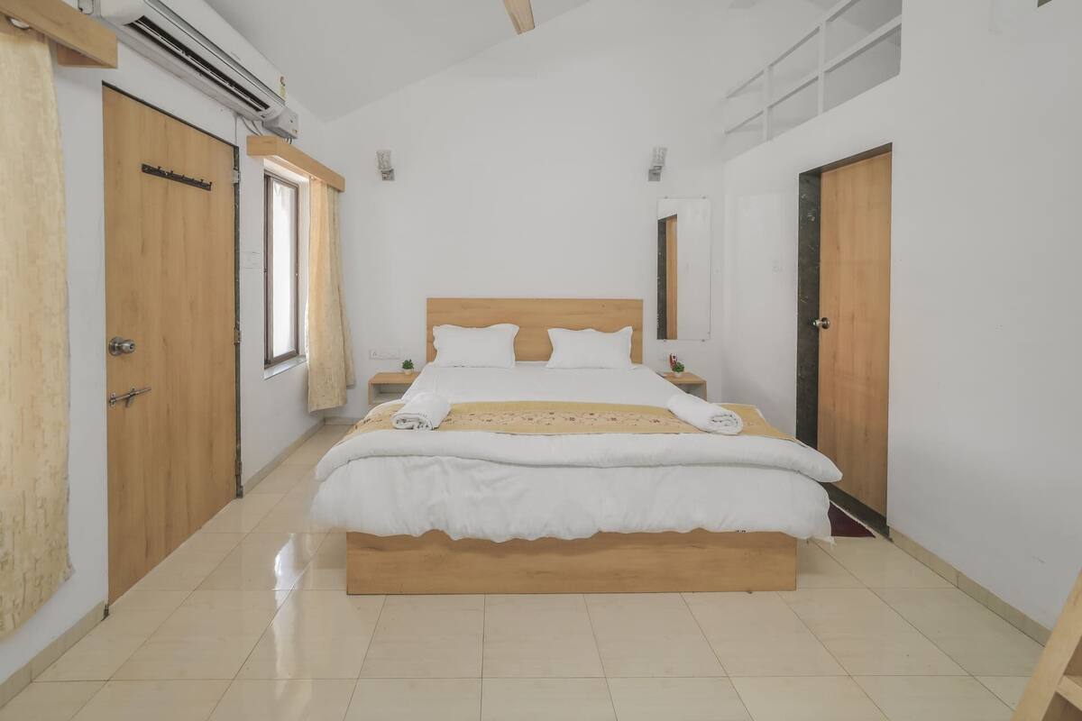 A bedroom with a wooden bed, a nightstand, and a window with curtains.
