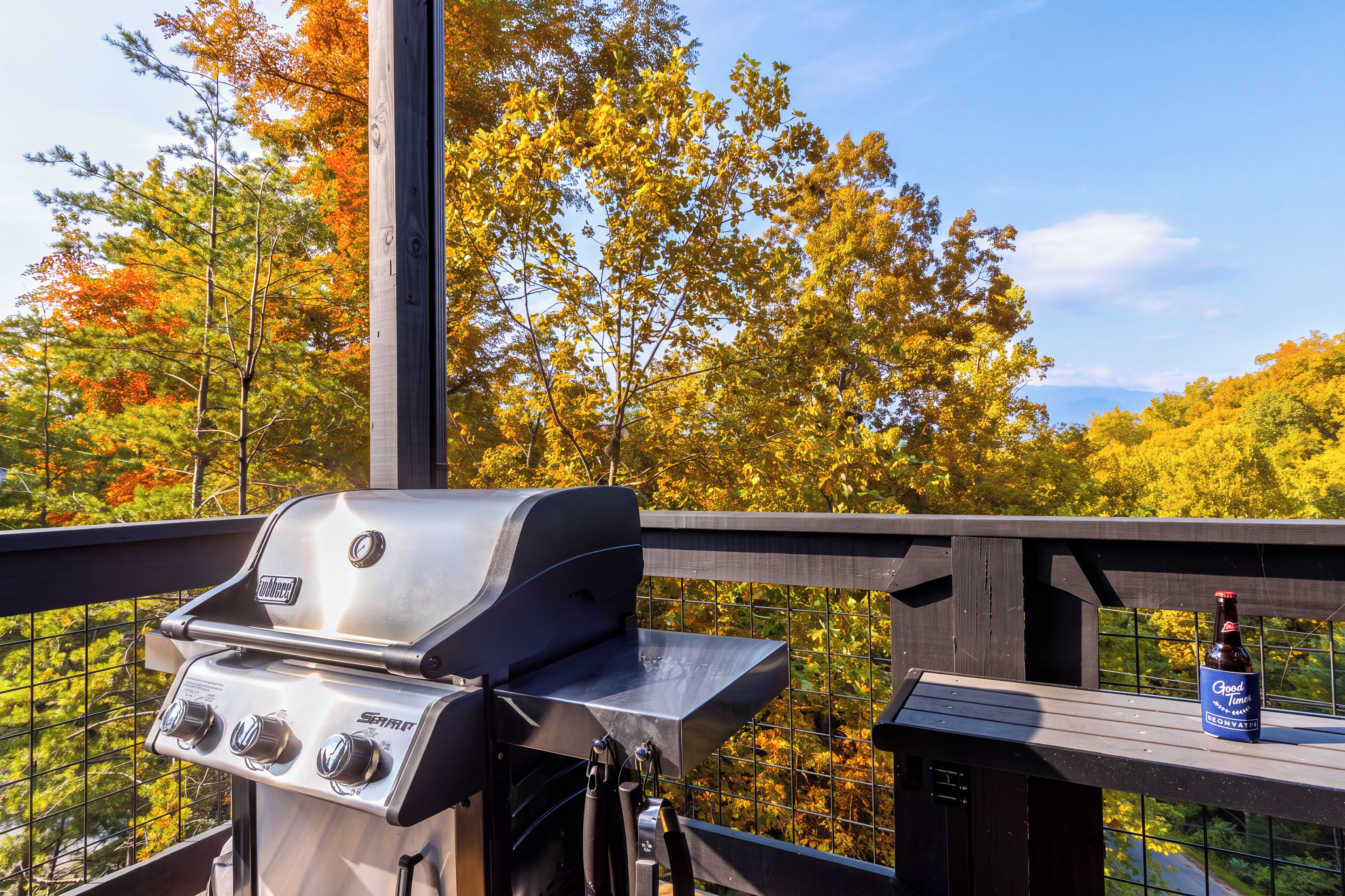Ein Grill auf einem Balkon mit Blick auf herbstliche Bäume.
