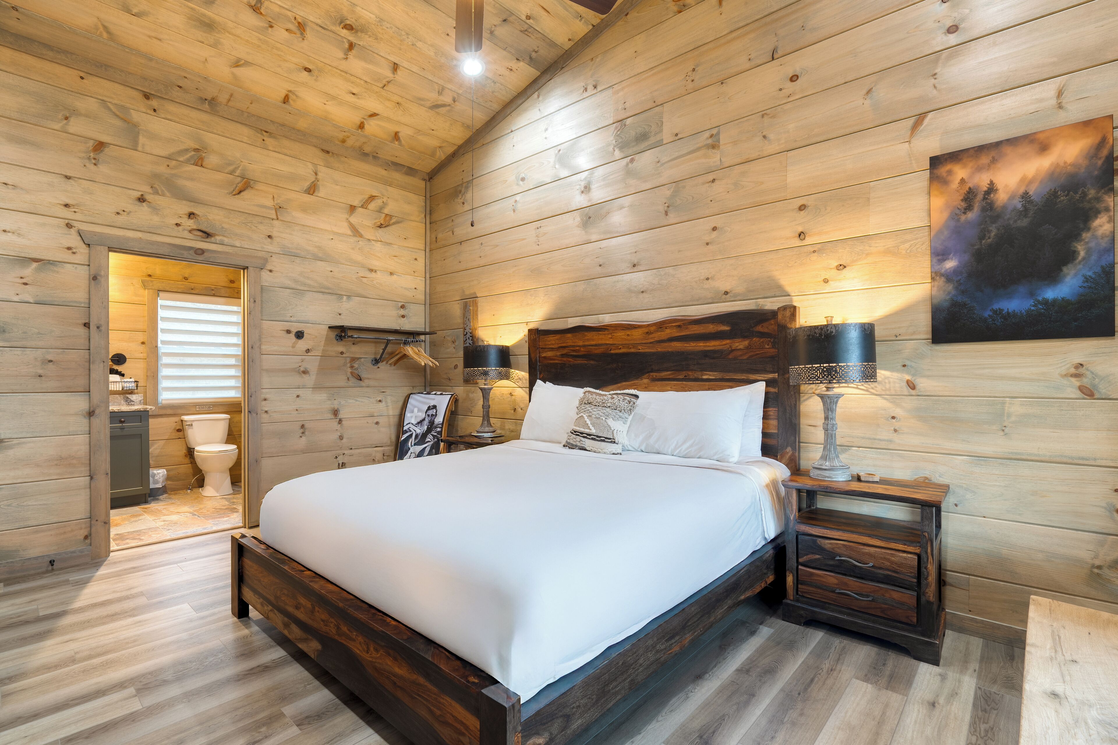 Ein Schlafzimmer mit Holzwandverkleidung, einem großen Bett, Nachttischen und einem Gemälde an der Wand.