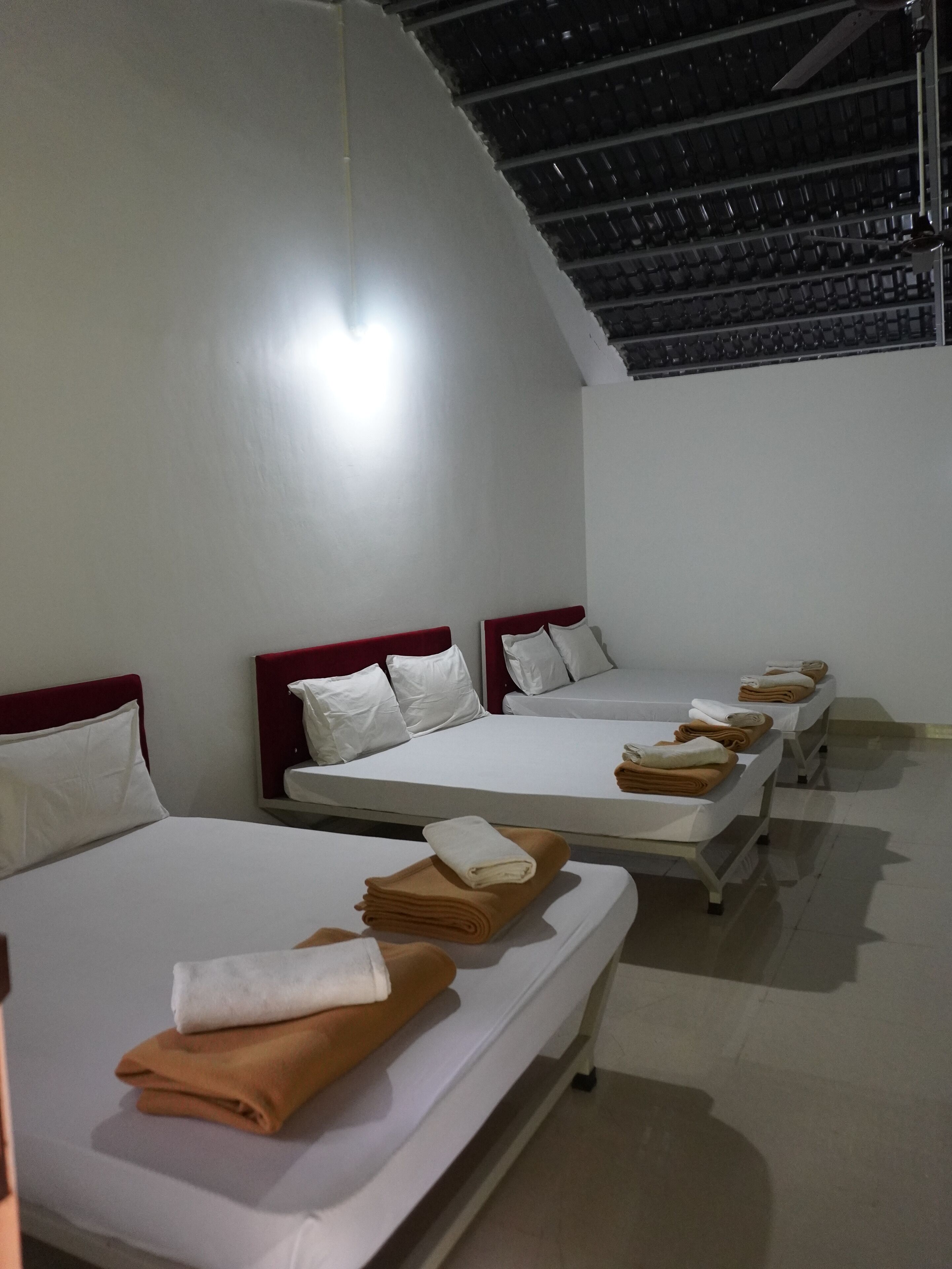 A hotel room with four beds arranged in a row, each with white linens and pillows.