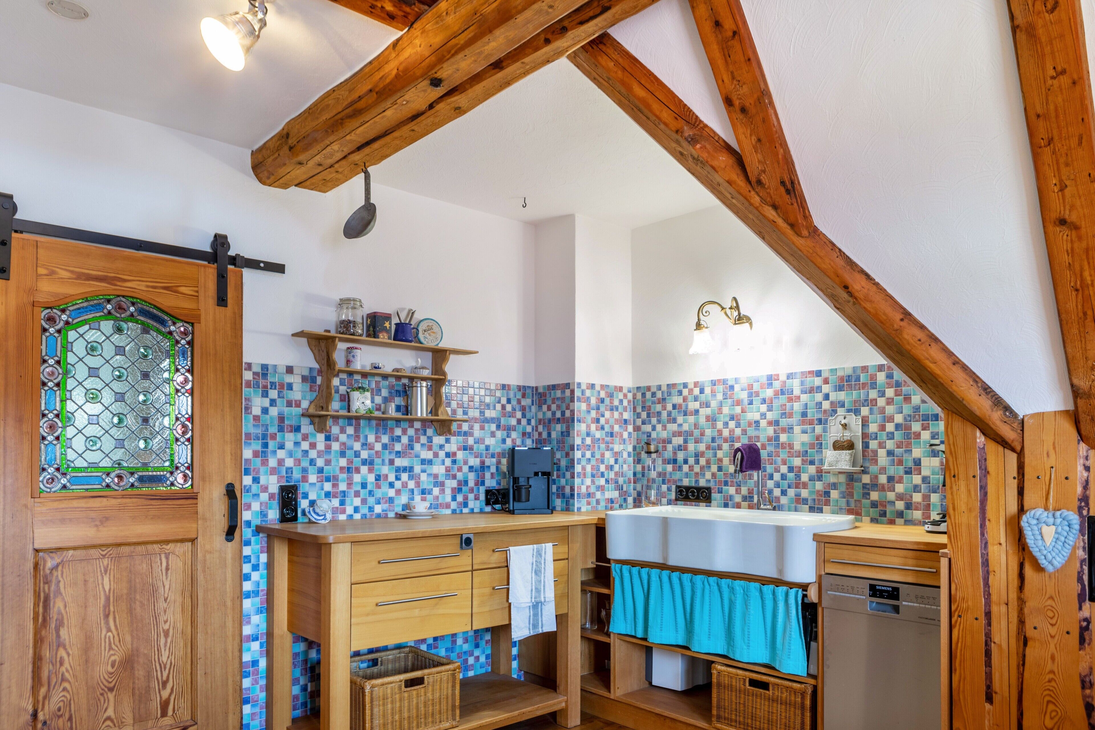 Eine Küche mit Holzbalken, einer Fliesenküchenwand, einer Spüle mit zwei Becken und einer Pendelleuchte.