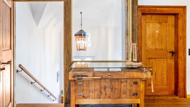 Ein Holzkabinent mit Spiegel, einer Pendelleuchte und einer Holztür.