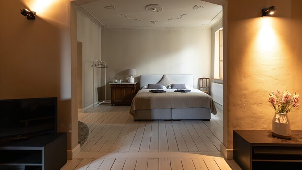 Ein Schlafzimmer mit Bett, Nachttischen, einer Lampe und einem Fernseher.