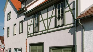 A traditional building with a gabled roof, multiple windows, and a set of green double doors.