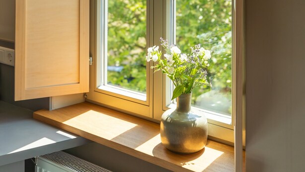 A window with a wooden frame and a vase with flowers on the sill. - Bright Boutique Apartment for a Relaxing Getaway (Großostheim)