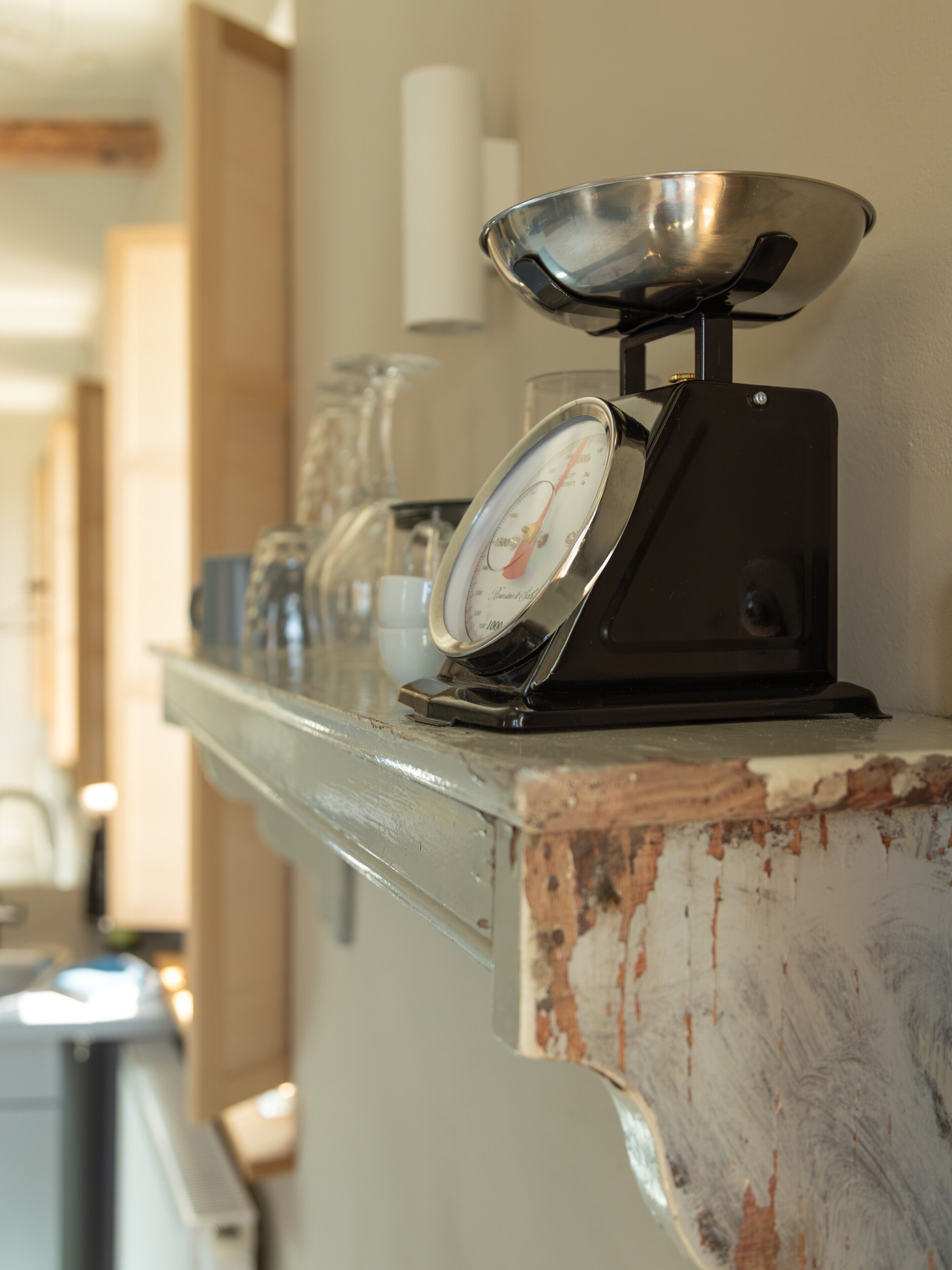 Un plan de travail de cuisine avec une balance, un récipient en verre et une tasse blanche.