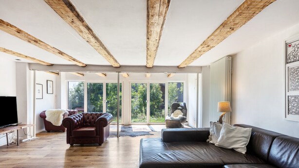A modern living room with a wooden ceiling, a leather sofa, a television, and a large window with a view of greenery. - Holiday Apartment Auf Dem Wald 6 Pers. with Mountain View, Private Terrace, and Wi-Fi (Görwihl)