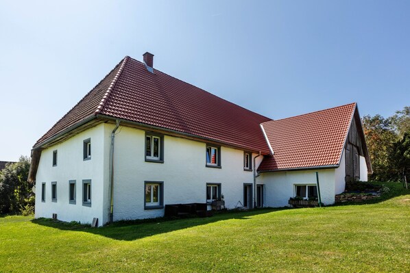 A two-story house with a red-tiled roof, a white exterior, and a well-maintained lawn. - Holiday Apartment Auf Dem Wald 6 Pers. with Mountain View, Private Terrace, and Wi-Fi (Görwihl)