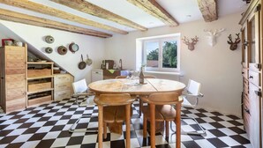 A kitchen with a checkered floor, wooden cabinets, a round table with chairs, and a window with a view of greenery. - Holiday Apartment Auf Dem Wald 6 Pers. with Mountain View, Private Terrace, and Wi-Fi (Görwihl)