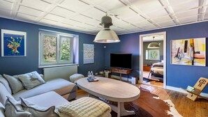 Een kamer met een bank, een tafel, een televisie en kunstwerken aan de muur.