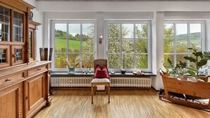 A room with large windows, a wooden cabinet, a chair, and a radiator. - Apartment 'On the City Wall' with Private Terrace and Wi-Fi (Schmallenberg)