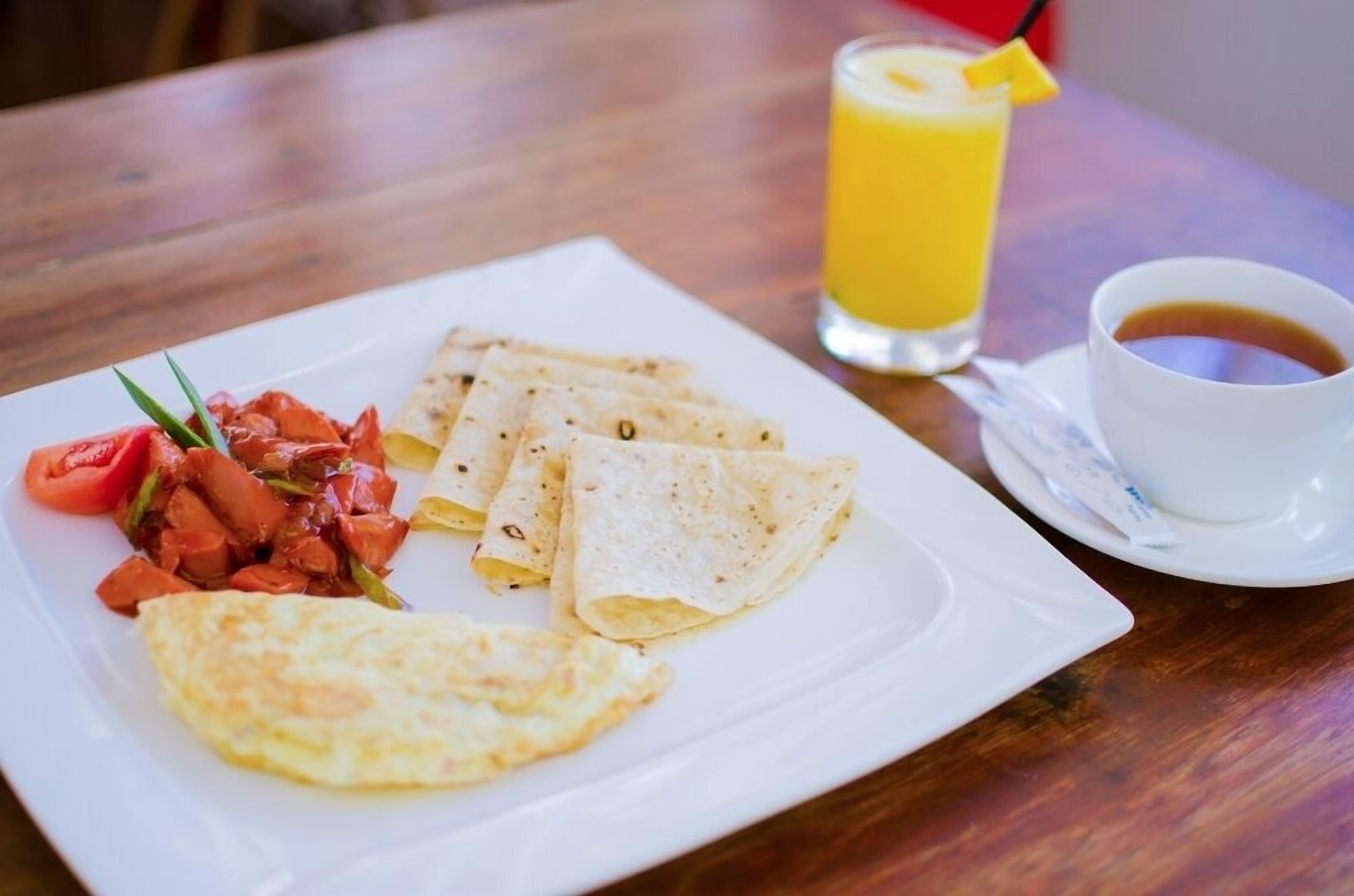 A breakfast plate with crepes, tomato salsa, and a cup of coffee on a wooden table.