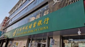 La façade d’un immeuble ornée d’une enseigne verte indiquant la présence de la Banque postale d’épargne de Chine.