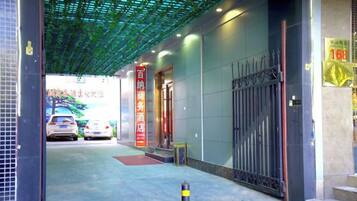 A hotel entrance with a covered walkway, a gated entrance, and a visible car in the background.