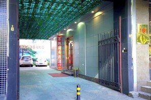 A hotel entrance with a covered walkway, a gated entrance, and a visible car in the background. - Baina Business Hotel (Shijiazhuang Zhongshan West Road Vientiane City Subway Station) (Shijiazhuang)