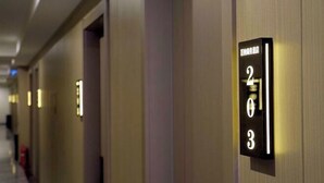 Un couloir d’hôtel avec des numéros de chambre illuminés sur le mur.