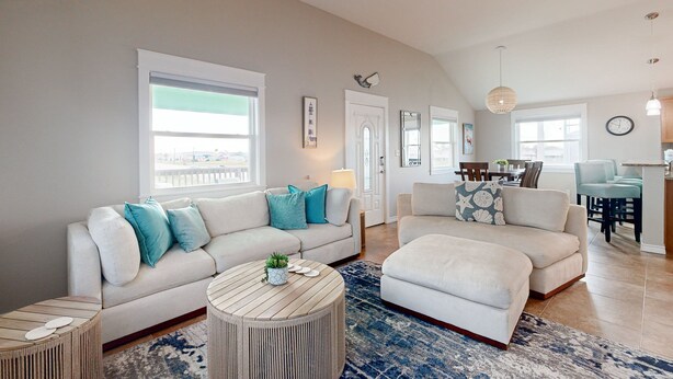 A spacious living area with a large window, a sofa set, and a dining table.
