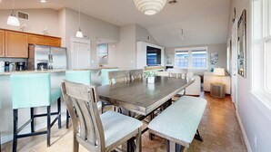 A spacious kitchen with a large island, wooden chairs, and a dining table.