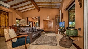 A spacious living room with a leather sofa, wicker armchair, and a television. - Villa Ashram 6 Emma Villas (Castelvetrano)