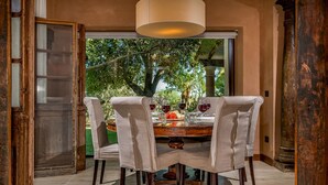 A dining area with a round table, four chairs, and a view of trees through a glass door. - Villa Ashram 6 Emma Villas (Castelvetrano)