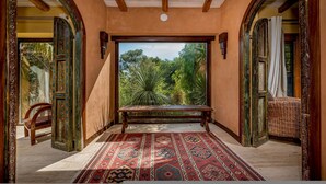 A room with a bench, a patterned rug, and a view of greenery through a large window. - Villa Ashram 6 Emma Villas (Castelvetrano)