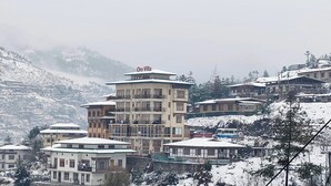 A multi-story building named "Oro Villa" with a traditional architectural style, surrounded by snow-covered houses and mountains in the background. - Hotel Oro Villa (Thimphu)