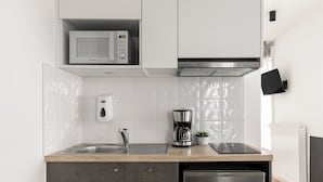 A modern kitchen with a built-in microwave, coffee maker, and refrigerator. - Montempo appart-hotel Noisy le Sec (Noisy-le-Sec)