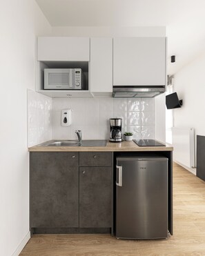 Una cucina moderna con forno a microonde, macchina del caffè e frigorifero integrati.