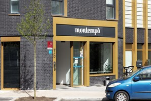 Un edificio con un letrero que dice 'montempò' y un coche azul estacionado frente a él.
