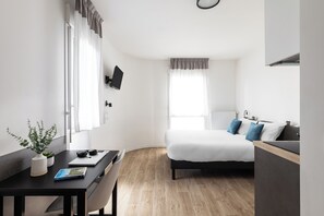 A modern hotel room with a bed, a desk with a laptop, a potted plant, and a window with curtains. - Montempo appart-hotel Noisy le Sec  (Noisy-le-Sec)