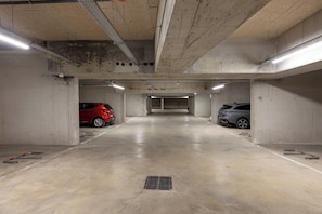 An underground parking garage with concrete walls, a flat floor, and overhead fluorescent lighting.