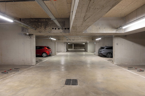 An underground parking garage with concrete walls, a flat floor, and overhead fluorescent lighting.