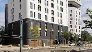 A multi-story hotel with a modern design, featuring a prominent entrance and a corner building with balconies. - Montempo appart-hotel Noisy le Sec  (Noisy-le-Sec)