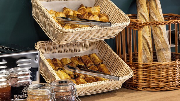 A breakfast buffet with baskets of pastries, bread, and oranges. - Montempo appart-hotel Noisy le Sec  (Noisy-le-Sec)