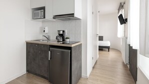 A modern kitchen with a built-in microwave, a coffee maker, and a compact refrigerator. - Montempo appart-hotel Noisy le Sec  (Noisy-le-Sec)