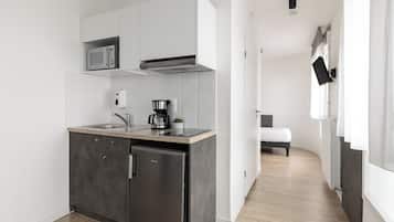 Een moderne keuken met een ingebouwde magnetron, een koffiezetapparaat en een compacte koelkast.