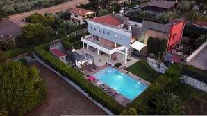 A modern two-story house with a swimming pool, surrounded by well-maintained gardens and a paved driveway. - Villa Tiberio 6 2 Emma Villas (Genzano di Roma)