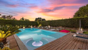 A swimming pool with lounge chairs and a hot tub, surrounded by a wooden deck and a hedge. - Villa Tiberio 6 2 Emma Villas (Genzano di Roma)