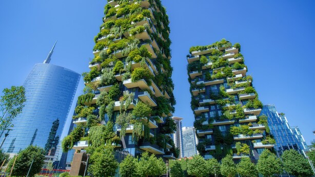 Een hoog gebouw met meerdere balkons vol begroeiing.