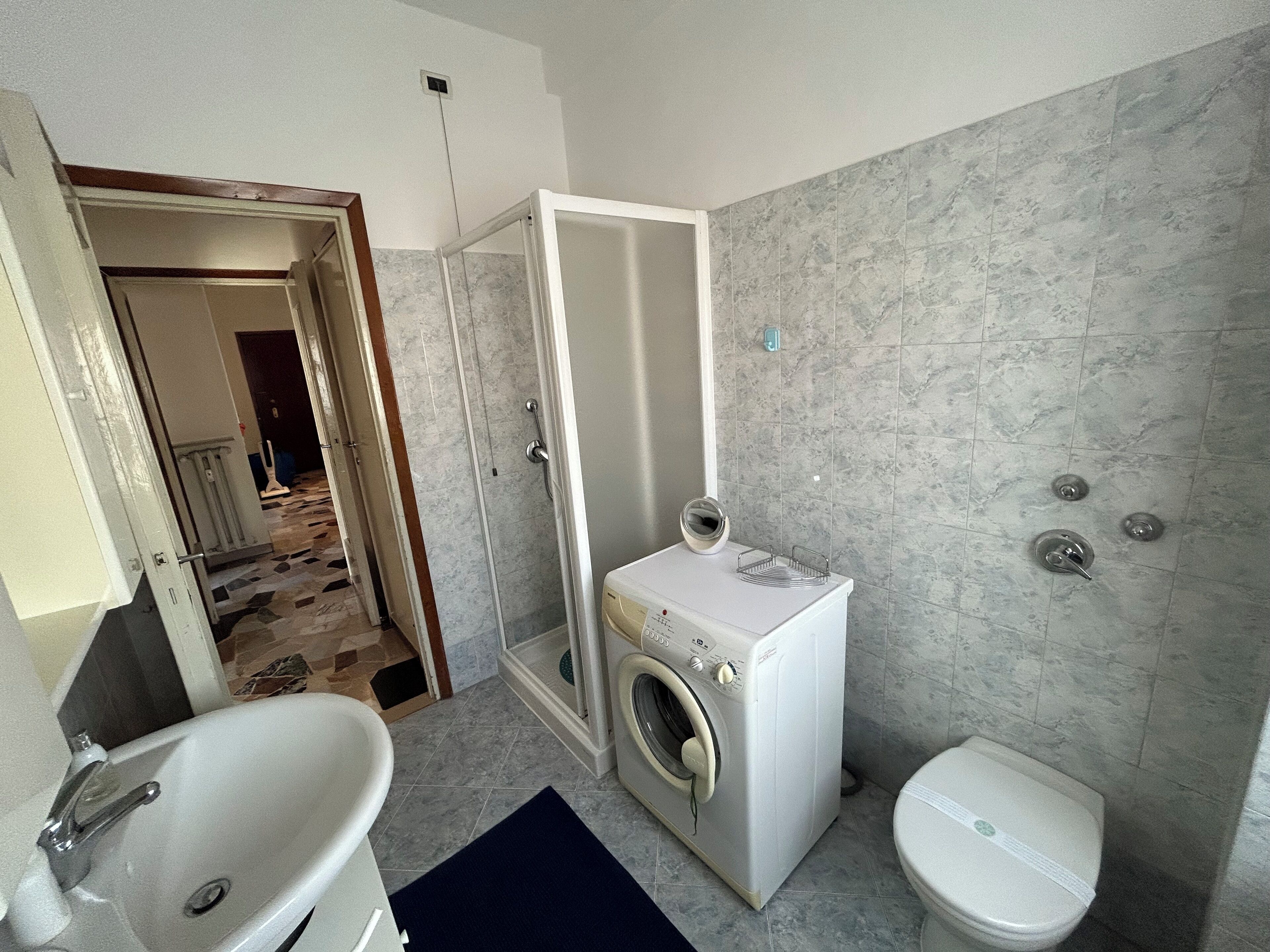 A bathroom with a sink, toilet, and washing machine.