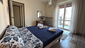 Een slaapkamer met een bed, een dressoir, een spiegel en een radiator.