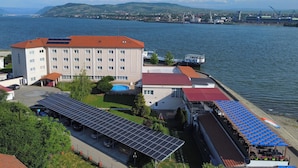 A hotel with a swimming pool, solar panels, and a view of the water.